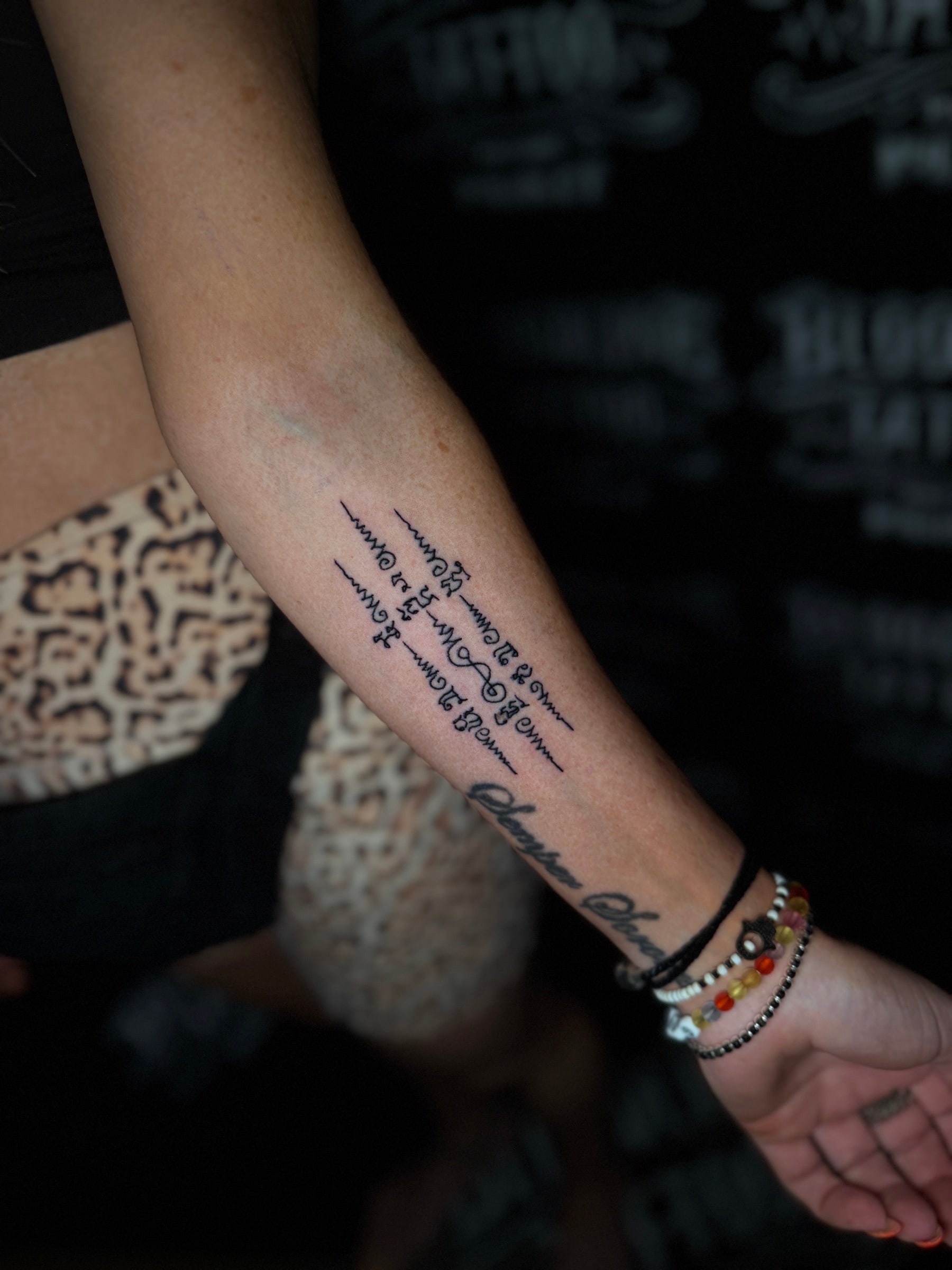 Sam Taew (Three Rows) Sak Yant with three vertical columns of sacred Khom script and unalome caps on the inner forearm at Bloodline Tattoo Phuket.
