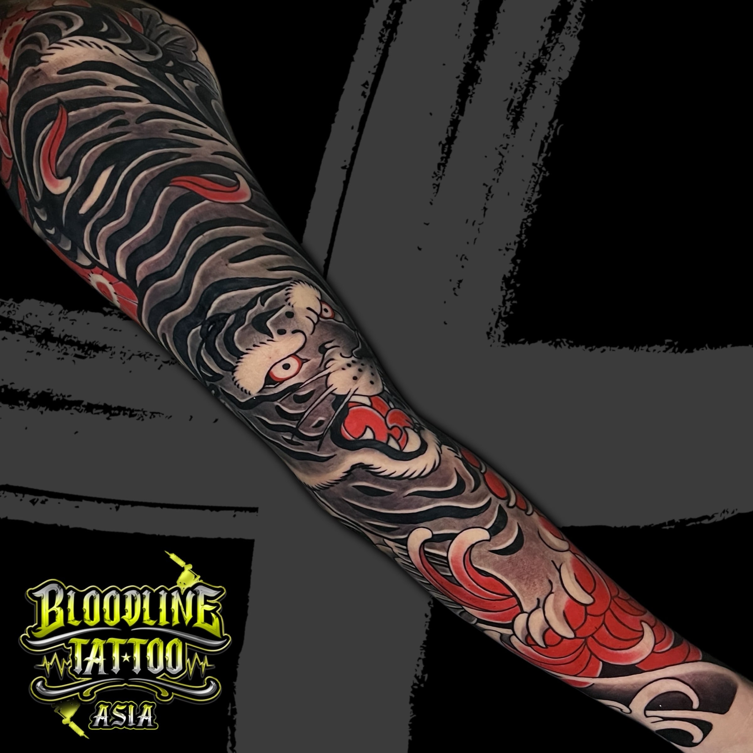 Colour Japanese Irezumi full sleeve tattoo of a snarling tiger in black, grey, and red with traditional wind bars at Bloodline Tattoo Bali.